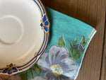 saucer with blue design on trim and blue napkin with flowers